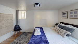 Bedroom with wood finished floors, baseboards, and a textured ceiling