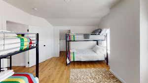 Bedroom featuring lofted ceiling, light wood-type flooring, and baseboards