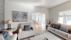 Living room with arched walkways and wood finished floors