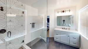 Bathroom featuring marble look tiles, a tile shower, and vanity