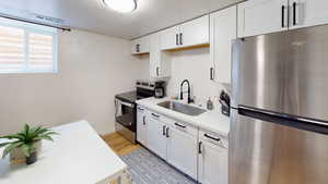 Kitchen featuring stainless steel appliances, a sink, light countertops, white cabinets, and a textured ceiling