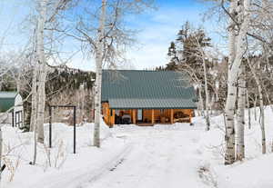 Snow covered property featuring a porch and metal roof