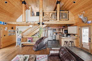 Living area featuring high vaulted ceiling, wood ceiling, wooden walls, and dark wood-style flooring
