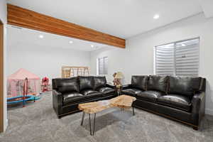 Carpeted living area with recessed lighting and beamed ceiling