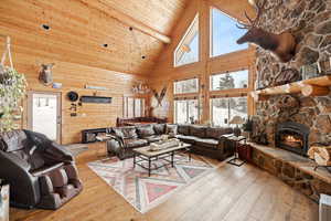 Living room with high vaulted ceiling, a fireplace, hardwood / wood-style flooring, and wood ceiling