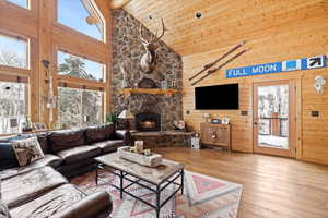 Living area featuring high vaulted ceiling, wood-type flooring, wooden ceiling, wood walls, and a fireplace