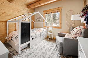 Carpeted bedroom with wooden ceiling, beamed ceiling, and wooden walls