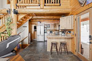 Kitchen with freestanding refrigerator, dishwasher, a peninsula, light countertops, and dark stone finish floors