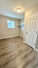 Washroom featuring wood finished floors, baseboards, a textured ceiling, and washer hookup