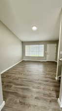 Unfurnished living room featuring baseboards and wood finished floors