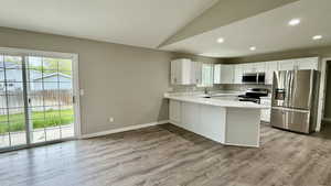 Kitchen featuring appliances with stainless steel finishes, healthy amount of natural light, a peninsula, vaulted ceiling, and a sink