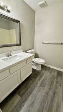 Bathroom featuring wood finished floors, toilet, vanity, and baseboards