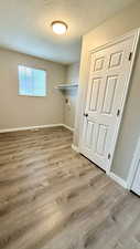 Laundry area featuring wood finished floors, baseboards, a textured ceiling, and hookup for a washing machine