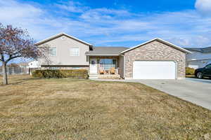 Split level home with concrete driveway, an attached garage, brick siding, and a porch