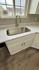 Kitchen view of a sink, white cabinetry, and dishwasher