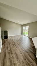 Unfurnished living room featuring dark wood-style floors and baseboards