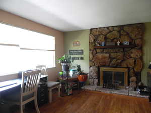 Home office with wood finished floors and a fireplace