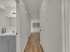 Hallway featuring a sink, light wood-style floors, and baseboards