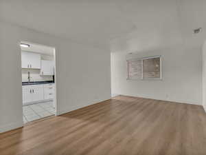 Spare room featuring light wood finished floors, a sink, and baseboards