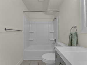 Bathroom with tile patterned flooring, toilet, vanity, baseboards, and shower / bath combination