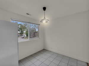 Unfurnished dining area with light tile patterned flooring and baseboards