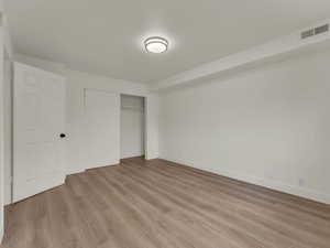 Unfurnished bedroom with light wood finished floors, a closet, and baseboards
