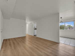 Unfurnished living room with light wood-style floors and baseboards