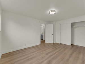 Unfurnished bedroom with light wood-style flooring, a closet, and baseboards
