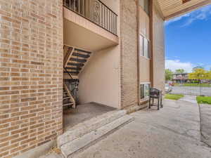 View of exterior entry featuring brick siding and fence