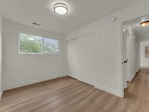 Unfurnished bedroom featuring light wood finished floors, a closet, and baseboards