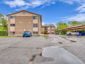 View of property featuring covered and uncovered parking