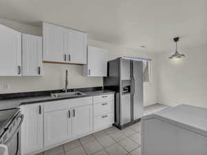 Kitchen with stainless steel appliances, a sink, white cabinetry, washer / clothes dryer, and hanging light fixtures