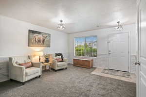 Living area featuring a wainscoted wall, a textured ceiling, carpet floors, and a chandelier