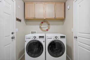 Laundry area featuring cabinet space, washer and clothes dryer, and baseboards