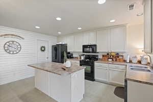 Kitchen with black appliances, a sink, a center island, recessed lighting, and white cabinets