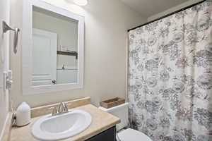 Full bathroom with vanity, toilet, and a shower with shower curtain