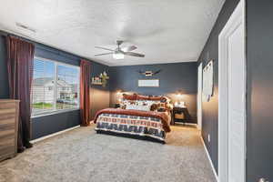 Bedroom featuring carpet floors, baseboards, a textured ceiling, and ceiling fan
