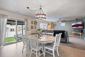 Dining room featuring ceiling fan, a textured ceiling, a chandelier, baseboards, and light tile patterned flooring