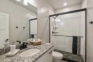 Bathroom featuring toilet, a shower stall, vanity, and recessed lighting