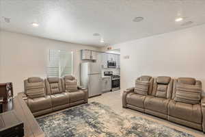 Living area featuring light wood-style floors, a textured ceiling, and recessed lighting