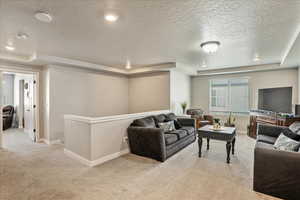 Living room featuring a tray ceiling, light colored carpet, baseboards, and a textured ceiling