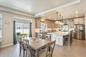 Dining room featuring light wood-type flooring, a textured ceiling, recessed lighting, and baseboards