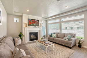 Living area featuring plenty of natural light, light wood finished floors, a textured ceiling, baseboards, and recessed lighting