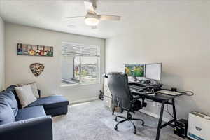 Carpeted office space with a textured ceiling, baseboards, and ceiling fan