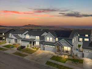Traditional-style house with an attached garage, driveway, fence, stone siding, and roof mounted solar panels