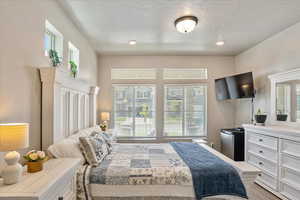 Bedroom with a textured ceiling, fridge, recessed lighting, and light wood finished floors