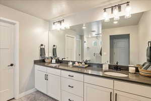Full bath featuring double vanity, walk in shower, baseboards, and tile patterned flooring