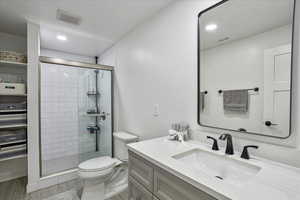 Bathroom featuring a shower stall, toilet, vanity, and wood finished floors