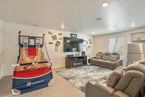 Living room featuring a textured ceiling, wood finished floors, baseboards, and recessed lighting