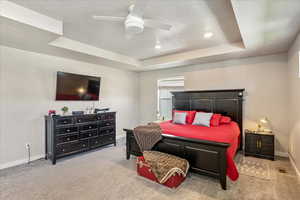 Bedroom featuring a tray ceiling, carpet floors, baseboards, recessed lighting, and ceiling fan